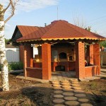 Colonne potenti con ringhiera in mezzo mattone tra di loro. Se necessario, questo gazebo estivo può essere facilmente convertito in uno invernale: metti finestre con doppi vetri o infissi in legno