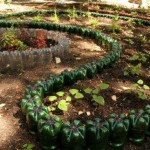 Las botellas de tamaño y color combinados crean un hermoso recinto. Los macizos de flores de bricolaje y los macizos de flores con su ayuda se pueden hacer en el campo o cerca de una casa privada.