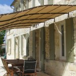 Pergola leggera sopra l'ingresso: una tenda da sole è tesa su un telaio metallico