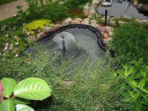 Se ve un recipiente de plástico y la bomba está en la parte inferior, justo en el lugar donde una tubería sobresale del agua.