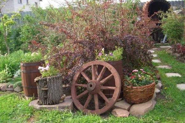 Il design rustico del giardino è facilmente riconoscibile dalla presenza di ruote di carrelli, cestini, piatti in ceramica, che vengono utilizzati nei modi più inaspettati