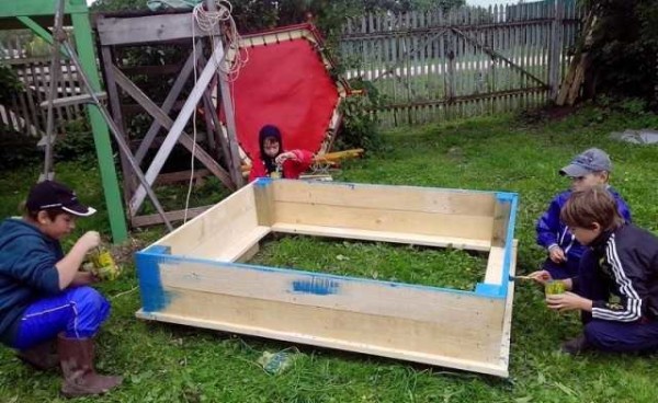 Pintar una caja de arena en cuatro pares de manos