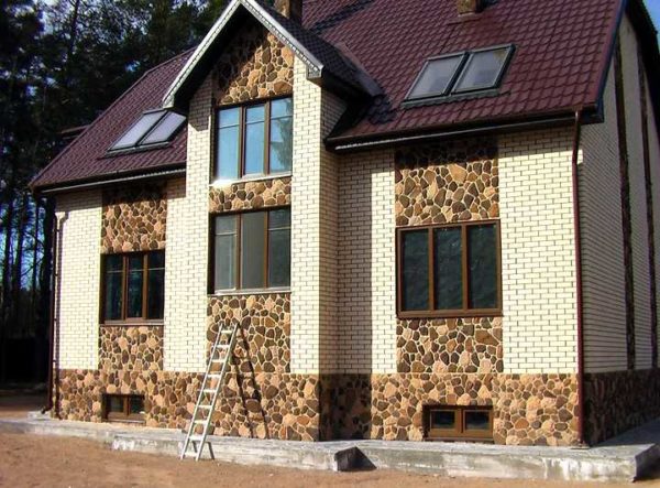 El ladrillo combina bien con la piedra. En la foto: una casa de ladrillo blanco con adornos de piedra salvaje.